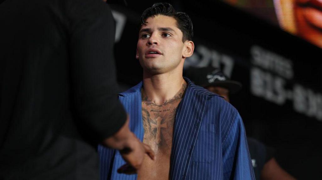 Ryan Garcia is pictured at a weigh-in with his blue shirt open