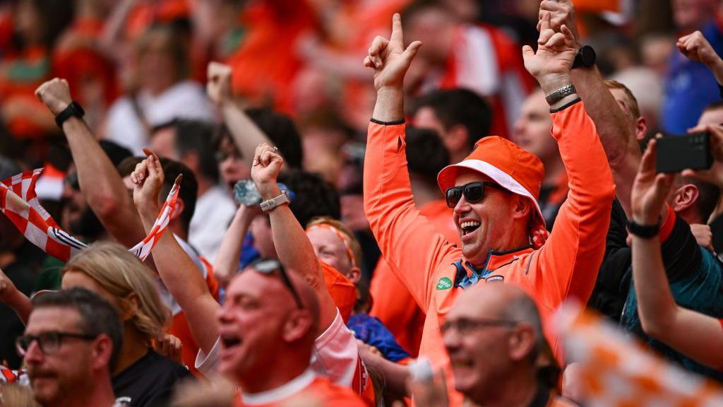 Armagh fans wearing orange in crowd celebrating during semi-final victory against Kerry