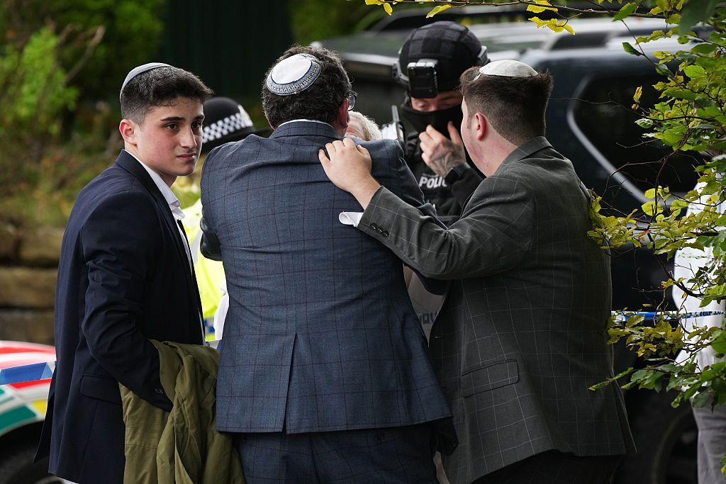 Members of the Jewish community embrace each other as they stand next to police officers outside Heaton Park Synagogue in Manchester following the attack.