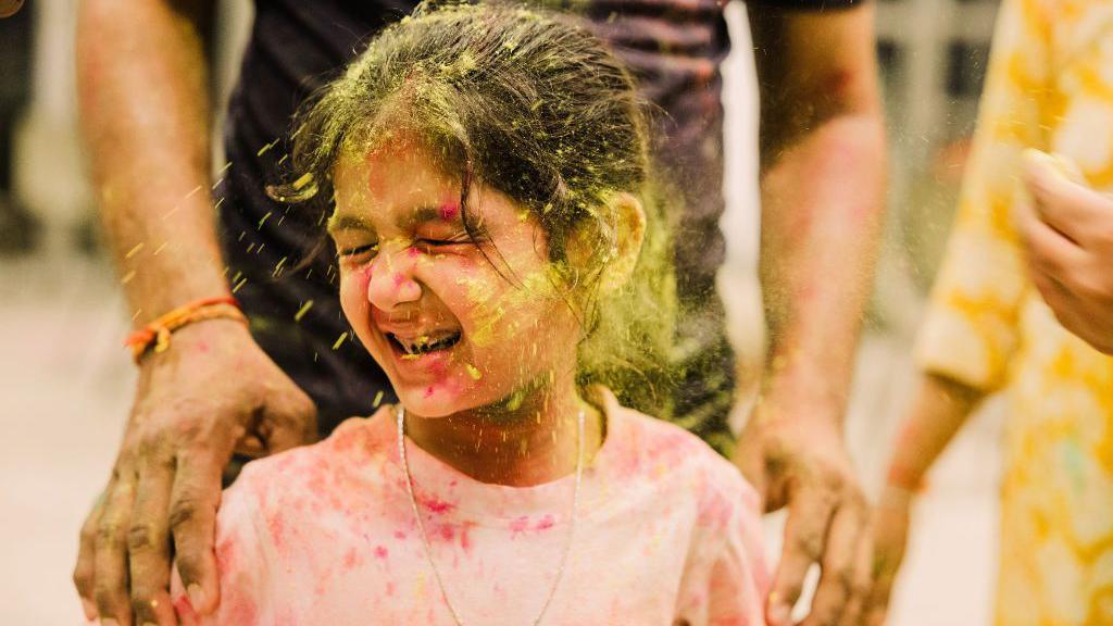 A youngster has yellow powder paint thrown at her during the Holi festivities in Durban, South Africa - Thursday 13 March 2025