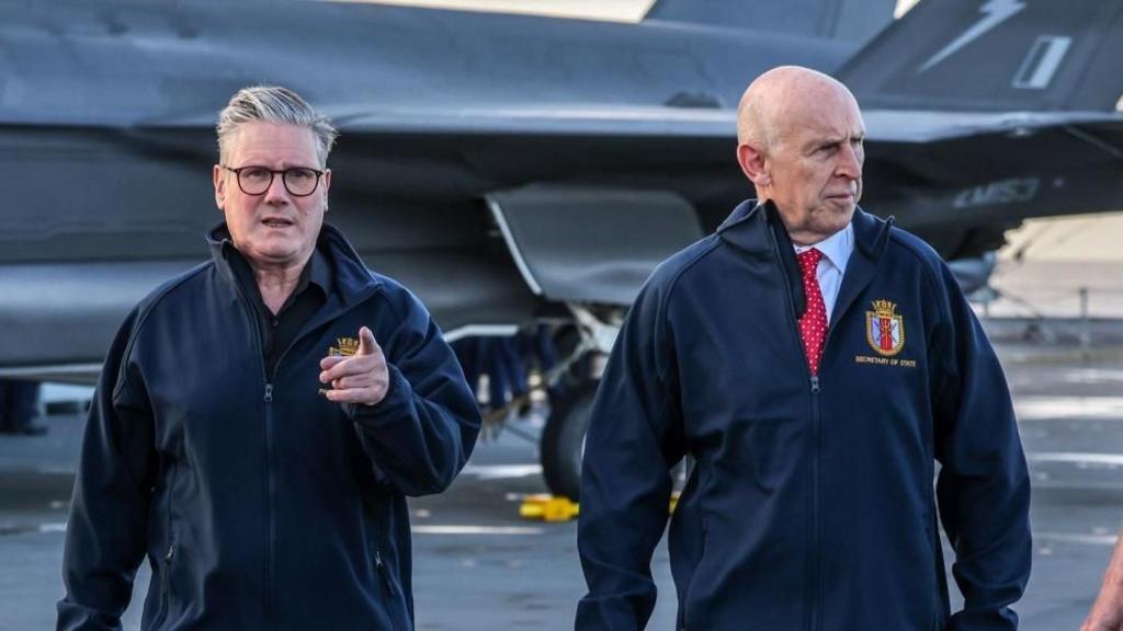 Prime Minister Keir Starmer (second left) and Defence Secretary John Healy (second right) talk with naval officers on the flight deck of HMS Prince of Wales