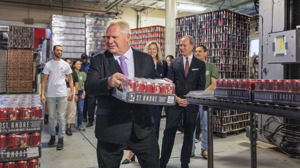 Premier Doug Ford a flat of beer cans during a photo-op at Cool Beer Brewing Company in Toronto, July 10, 2024