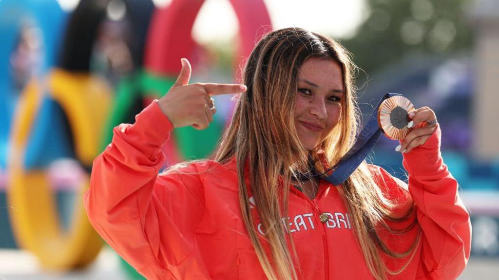 Sky Brown points at her Bronze medal 