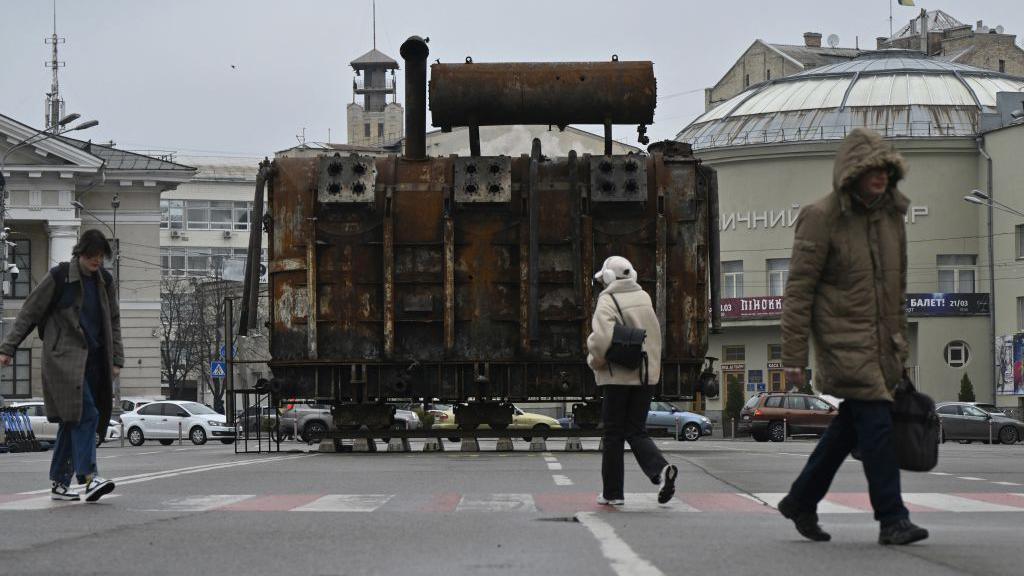 People walk past an equipment retrieved from a Ukrainian power plant struck by Russian forces and put on display in the Podil neighbourhood of Kyiv on March 19, 2025.