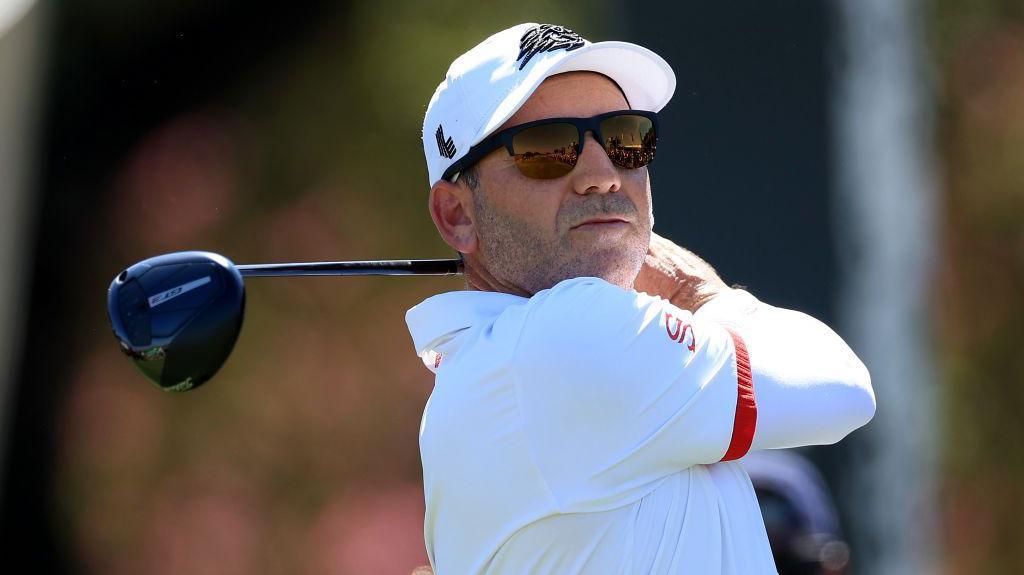 Sergio Garcia in sunglasses with a golf club after taking a shot