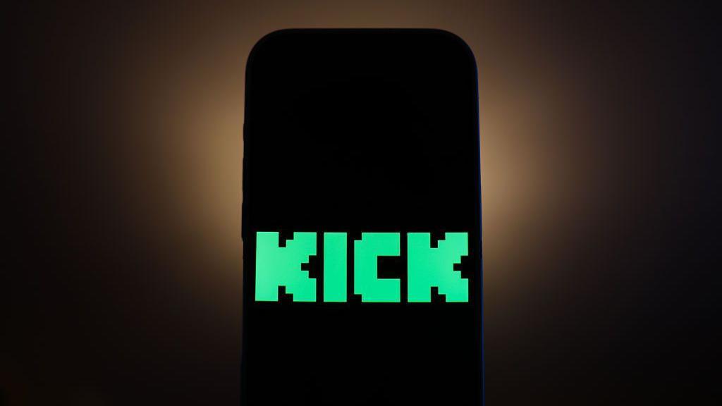 The green logo for the Kick streaming platform which is just Kick written in large green letters is displayed on a black phone