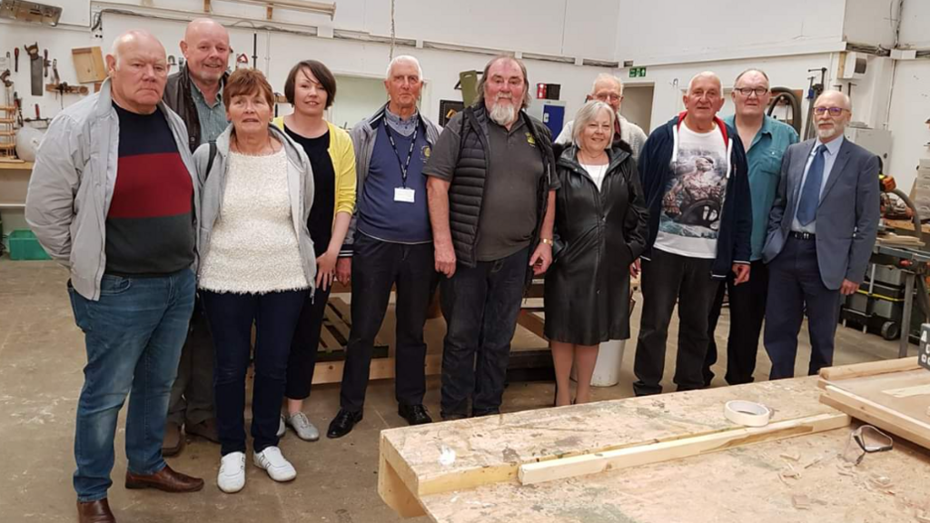 A group of 11 people of mixed gender and ages pose in the workshop of the Broadstairs Town Shed.
