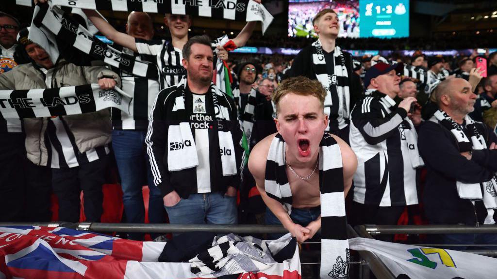 Newcastle United fans, in a sea of black and white shirts and scarves, celebrate winning the Carabao Cup