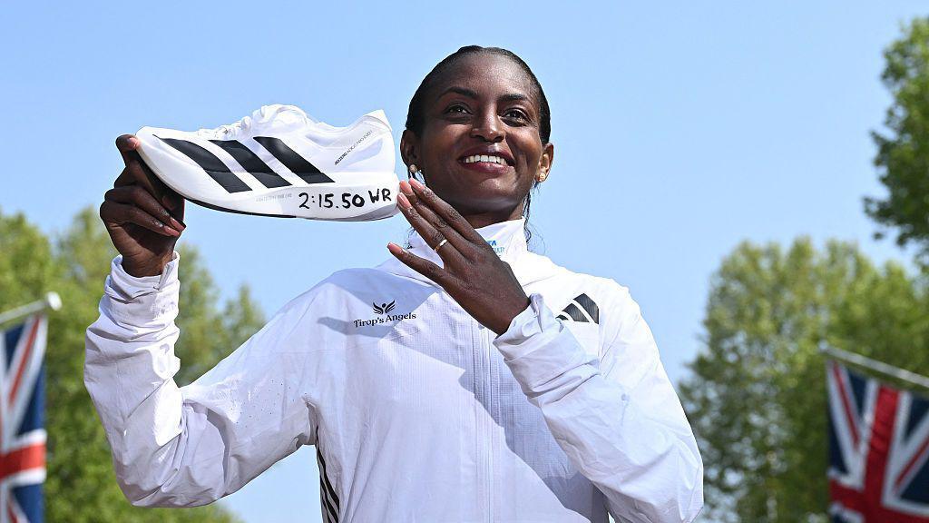 Tigst Assefa holds up a running shoe