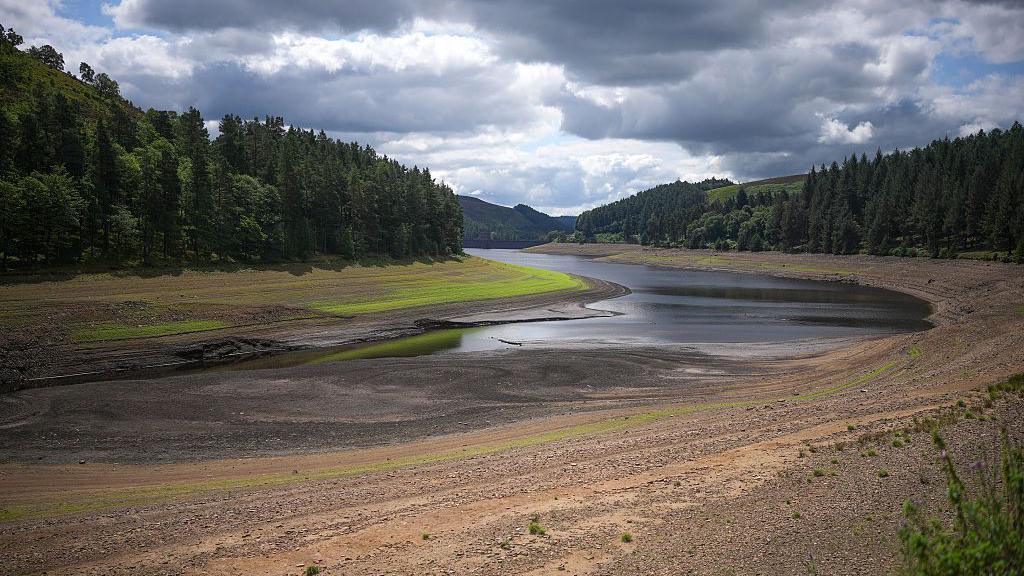 A reservoir looks very dry and has low water levels 