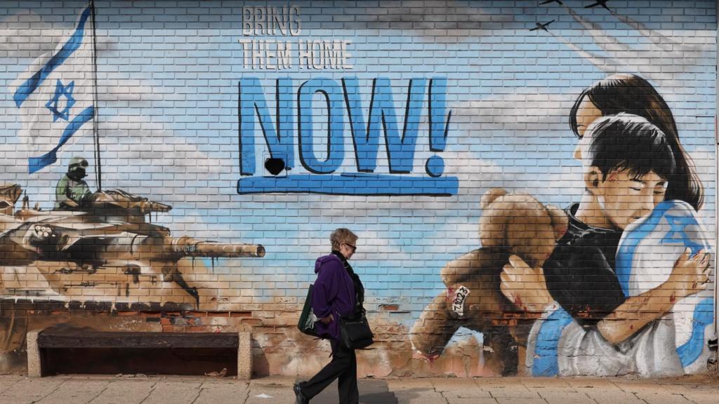 A woman walks past a mural reading 'Bring Them Home Now' calling for the release of Israeli hostages, who were abducted by militants during the 07 October 2023 Hamas attacks, in Kfar Saba, Israel, 17 January 2025