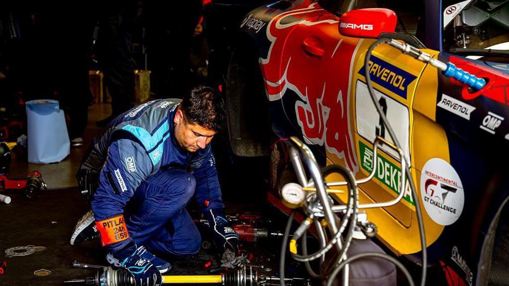 A mechanic tries to fix Max Verstappen's car at the Nurburging 24 hours
