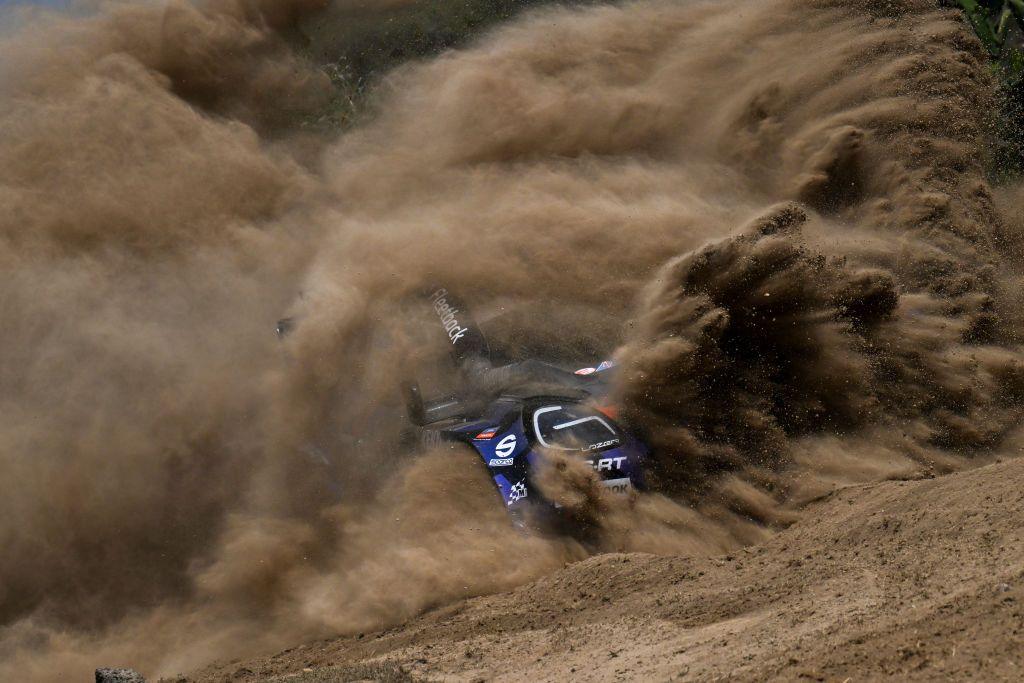 A car is almost buried in a haze of dust during a rally championship.