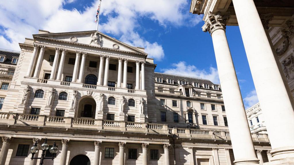 Frontal shot of the Bank of England building in the City of London. The building's facade is in the neo-classical style, built to resemble a Greco-Roman temple (tympanum at the top; six sets of twin columns to the front of an entrance porch, six statues of women at the bottom)