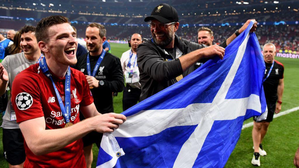 Andy Robertson and Jurgen Klopp hold a Scotland flag during 2019 Champions League celebrations.
