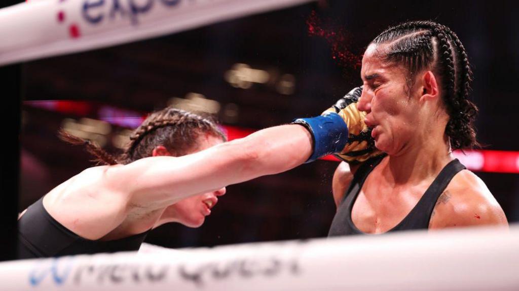 Blood flies off the face of Amanda Serrano as she is punched by Katie Taylor