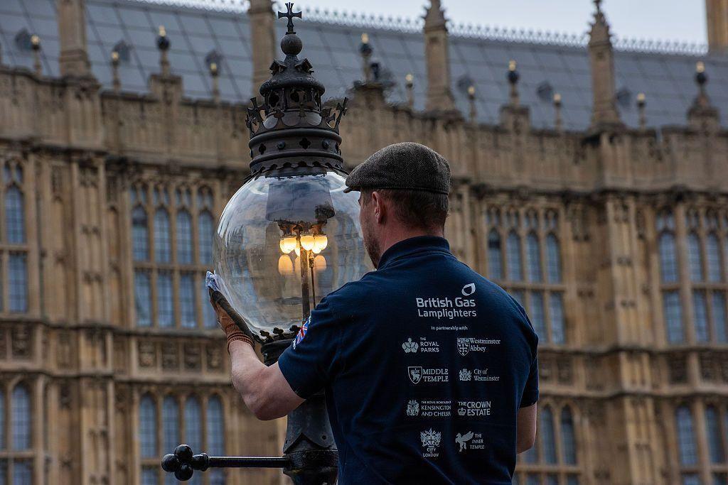 A London lamplighter gives a polish to the glass head of a lamp during the service
