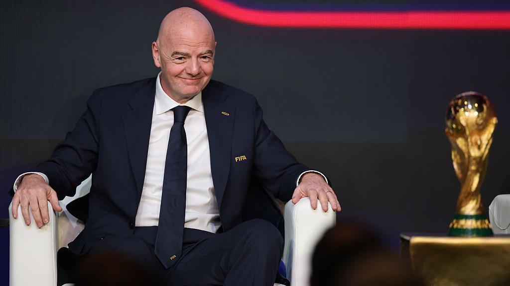 Gianni Infantino sat in a chair next to the World Cup trophy.