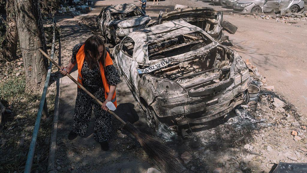 A woman sweeps the streets after damage from a Russian air strike in a residential area of Kyiv, Ukraine on 4July 2025.