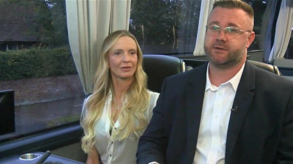 the male and female owners of a coach company, sat on one of their coaches while being interviewed by the BBC