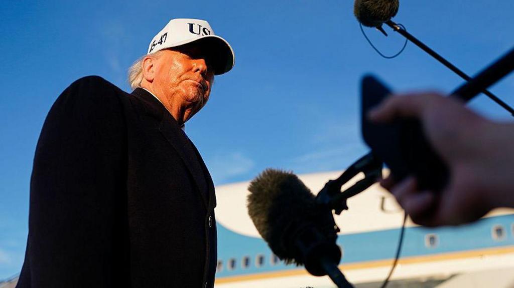 US President Donald Trump speaking into a microphone.