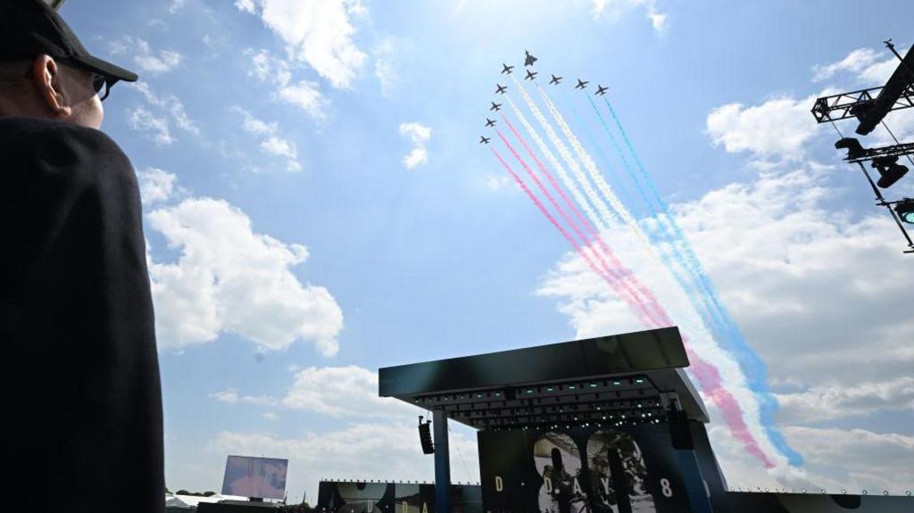 Red arrows flying over the stage of the D-Day 80 event in Southsea they are being watched by a veteran