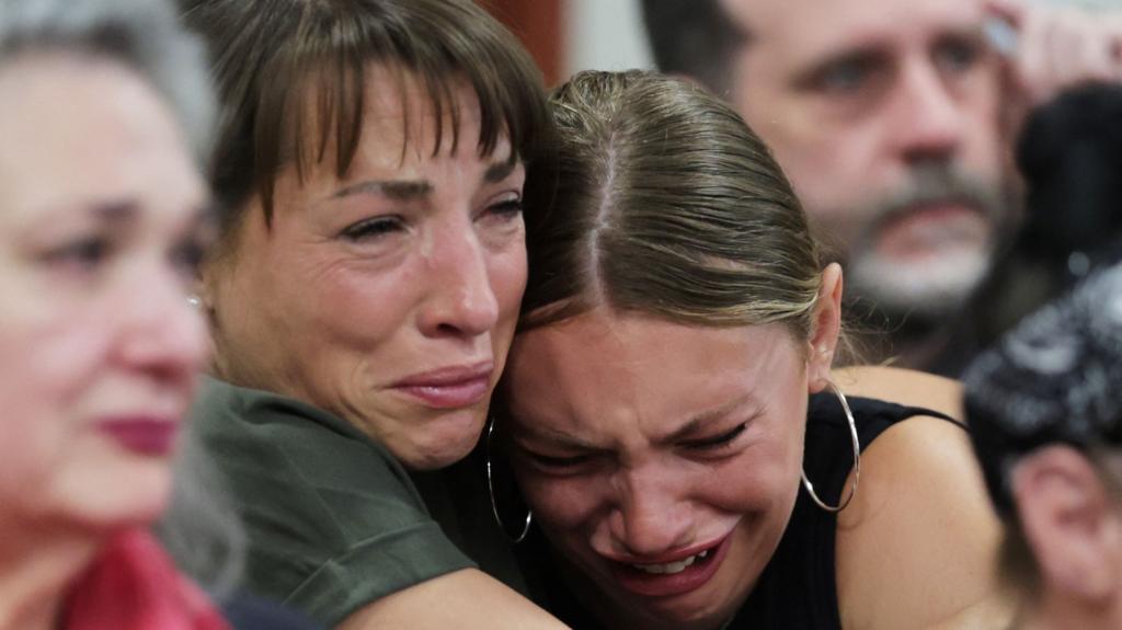 Dylan Mortensen gets a hug after speaking at the sentencing hearing of Bryan Kohberger after he was convicted - she looks extremely distressed and is having her head held