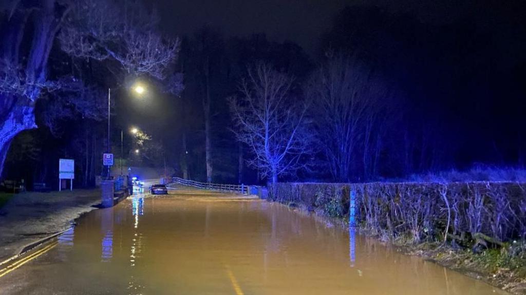 A car drives through a flooded ford