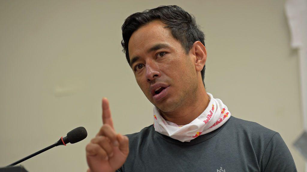 Nirmal Purja speaking into a microphone, with one finger raised