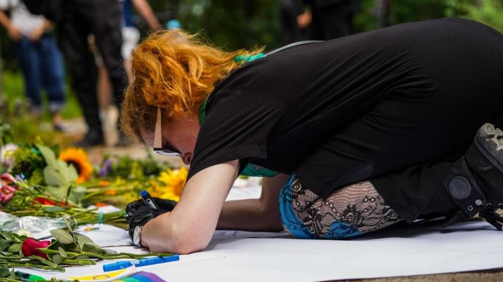 A person leaves a message near the scene where a vehicle plowed into a crowd on the sideline of the Christopher Street Day (CSD) parade in Berlin