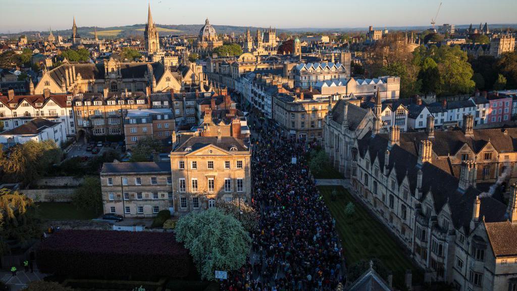 Crowds fill the streets as the Magdalen College Choir sing the Hymnus Eucharisticus from the top of the Great Tower, Magdalen College at Oxford University as the sun rises on May 1, 2018 in Oxford, England.
