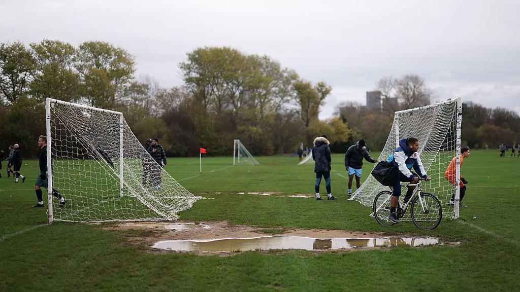 Football pitches and goals with a muddy puddle between them
