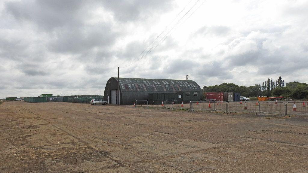 The runway at Bourn Airfield with silver barriers and a hangar