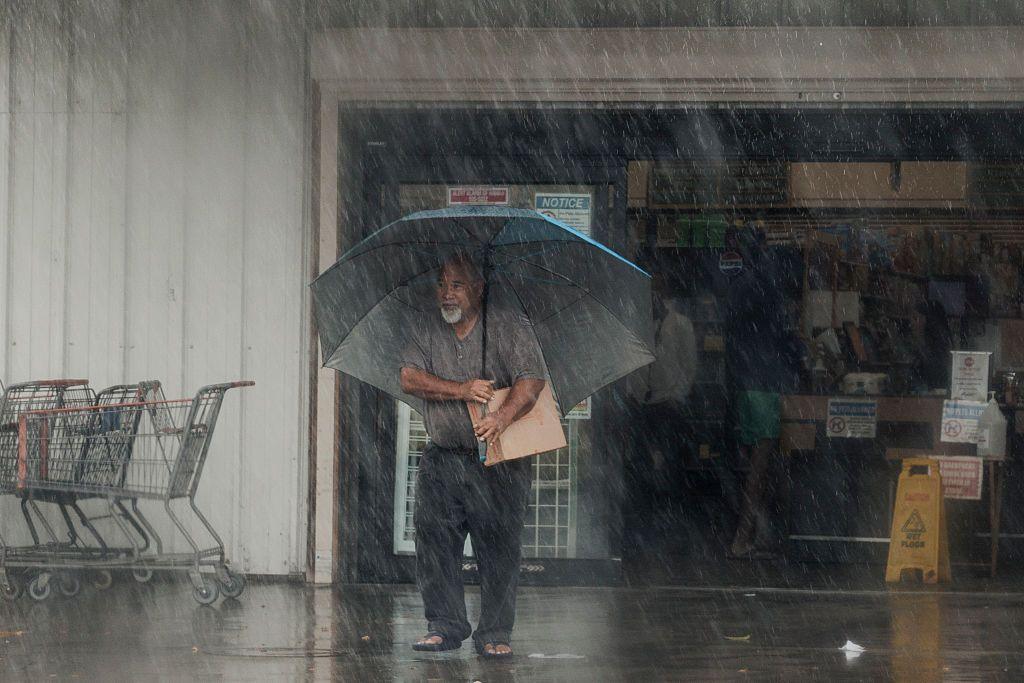 A man walks out of a shop carrying supplies