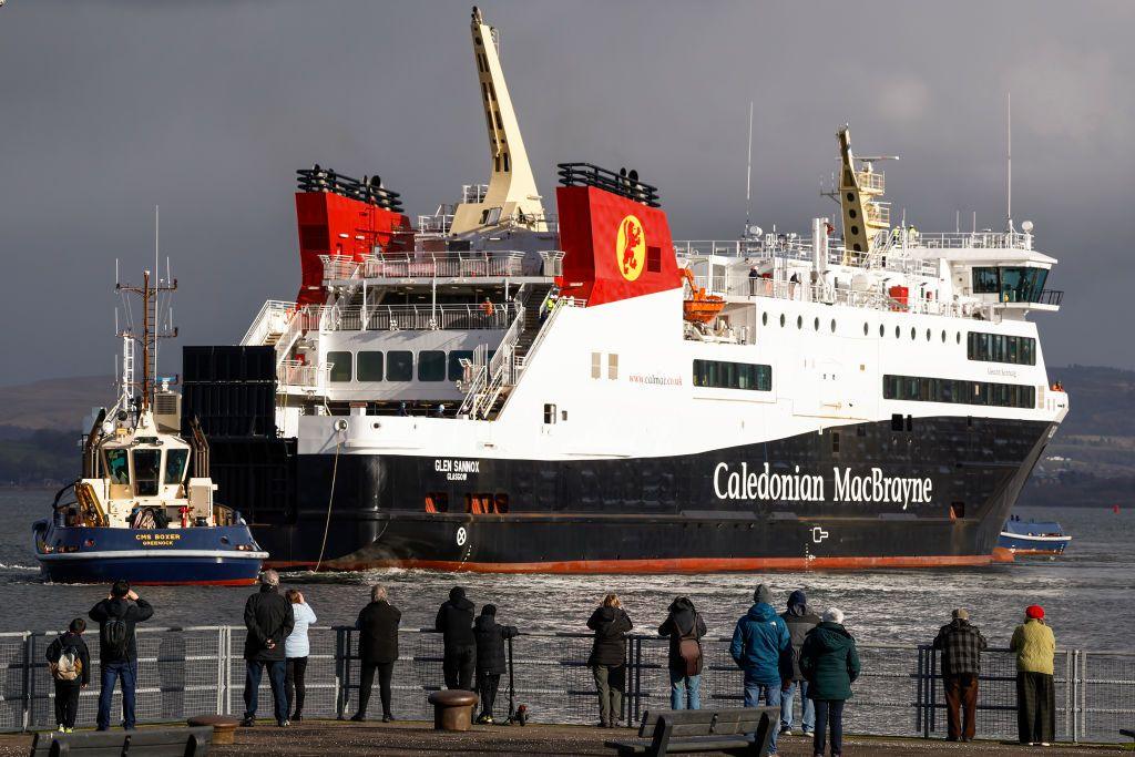 people on the harbourside look at a calmac ferry