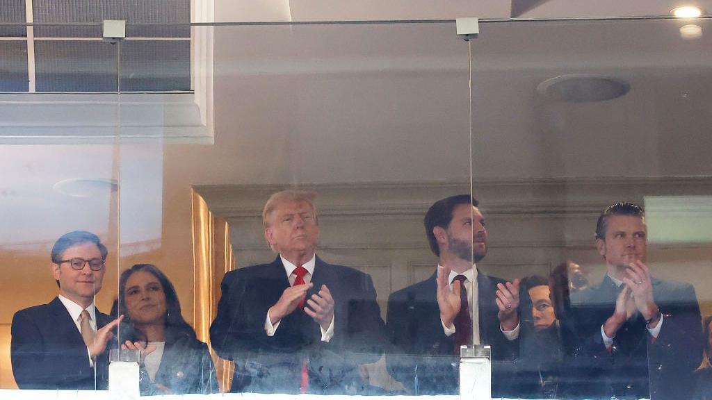 From left to right: Republican Speaker of the House Mike Johnson, National Intelligence Director nominee Tulsi Gabbard, President-elect Donald Trump, Vice-president-elect JD Vance, tech billionaire Elon Musk and defence secretary nominee Pete Hegseth. They are all clapping while watching the Army v Navy American football game from a box.