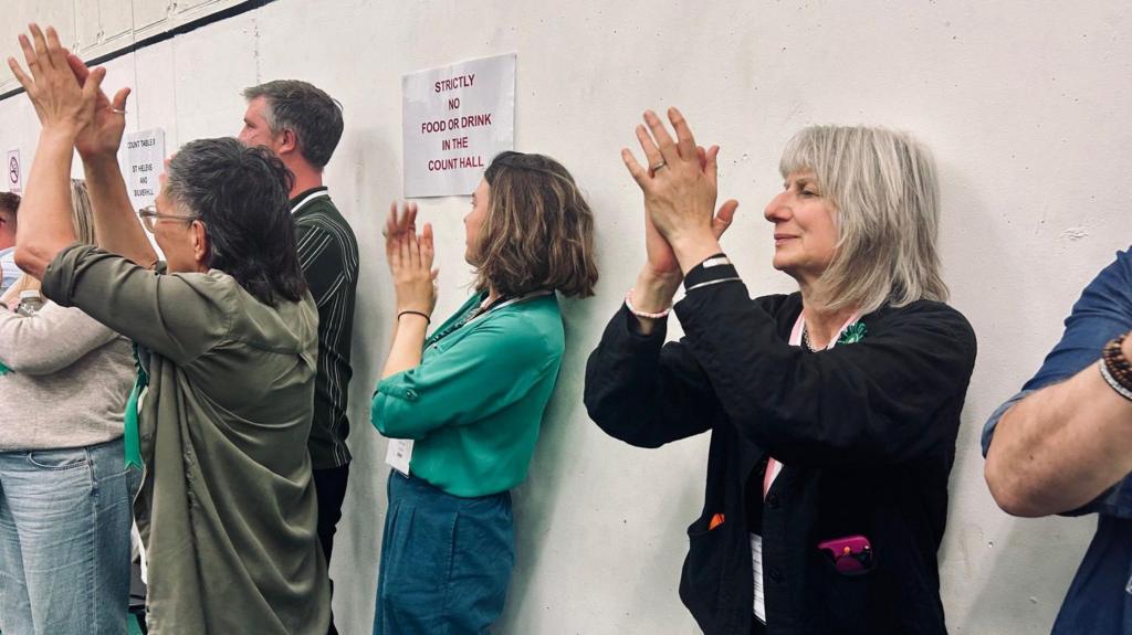 Crowds clap at an election count