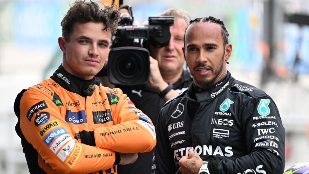 Lando Norris, with his arms folded, stood next to Lewis Hamilton