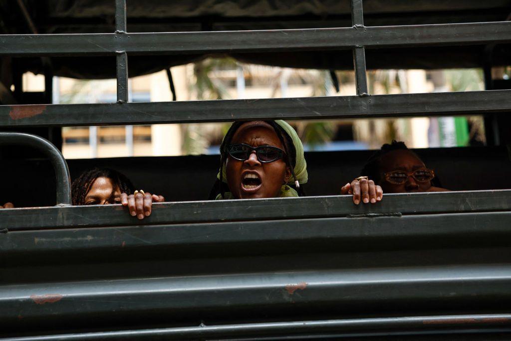 A woman who has been arrested shouts from a police wagon.