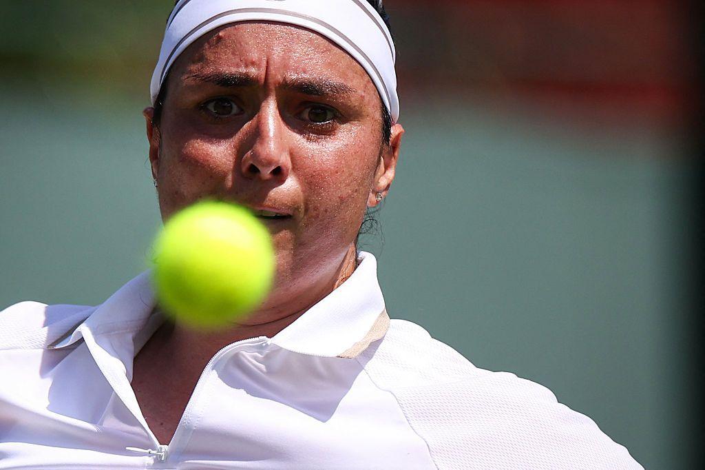 A tennis player stares intently at the ball in front of her face.