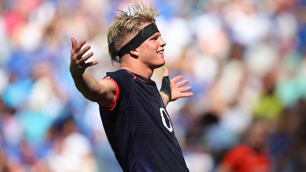 Henry Pollock, in England's dark blue jersey and wearing a black headband, celebrates with arms outstretched