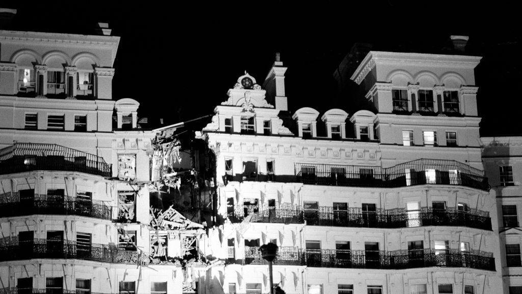 The front of a hotel is blown apart by a bomb blast.