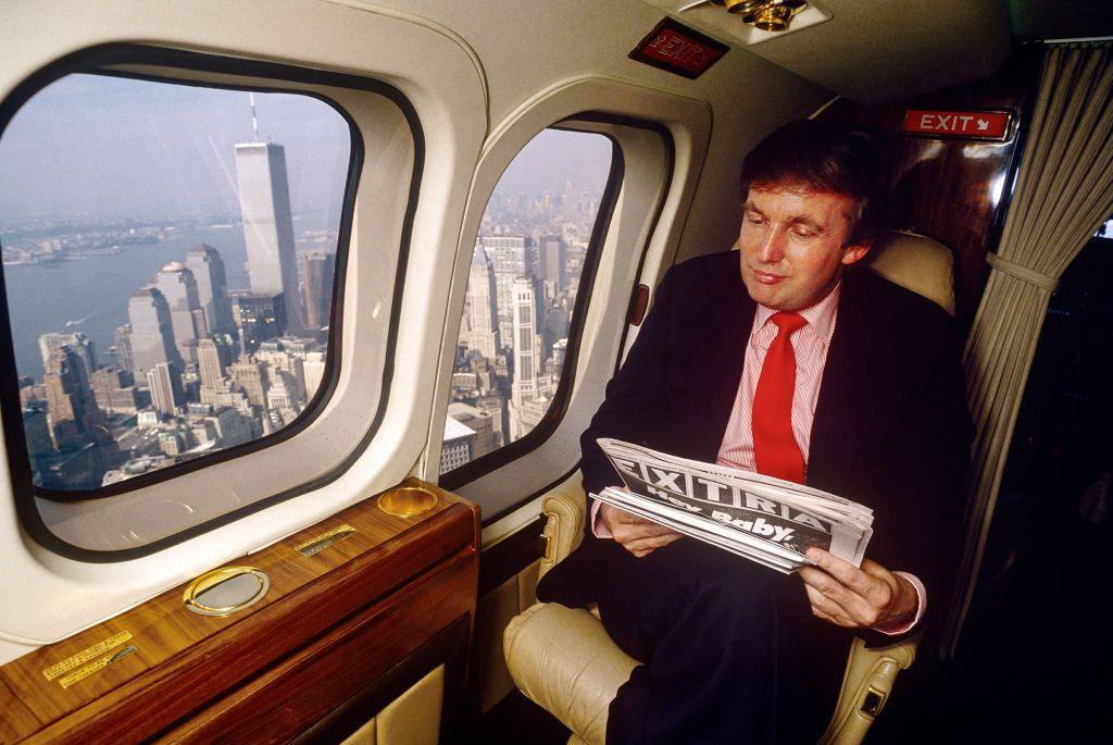 Donald Trump reads the newspaper in his helicopter while flying over the Twin Towers in New York .