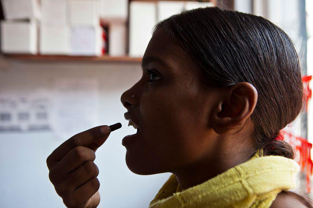 A patient swallows Tuberculosis (TB) medication in Delhi, India