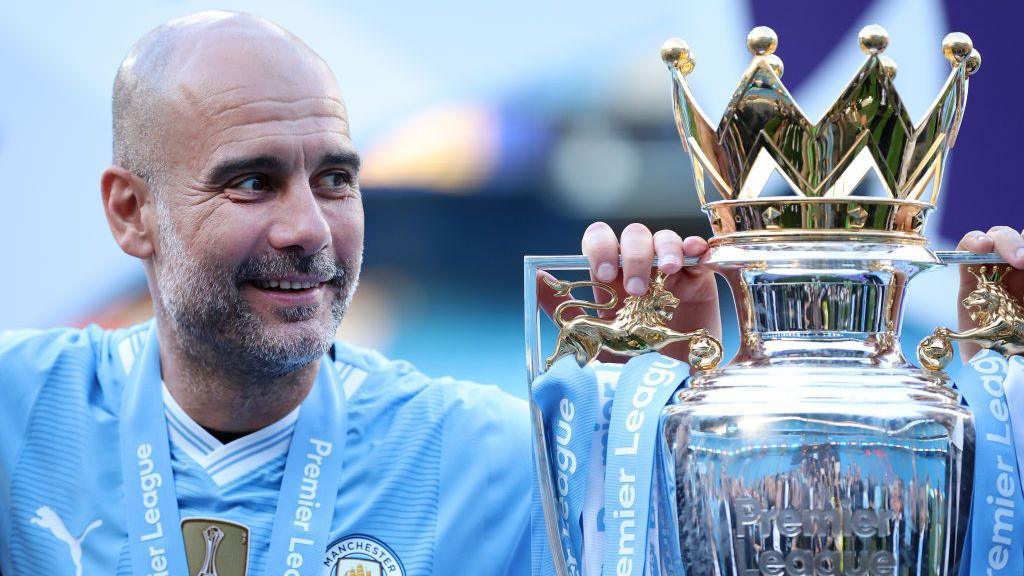 Manchester City manager Pep Guardiola smiles at the Premier League trophy