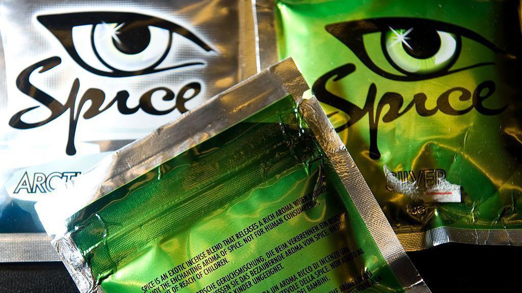 Packets of Spice on display in a shop with shiny green and silver packaging.