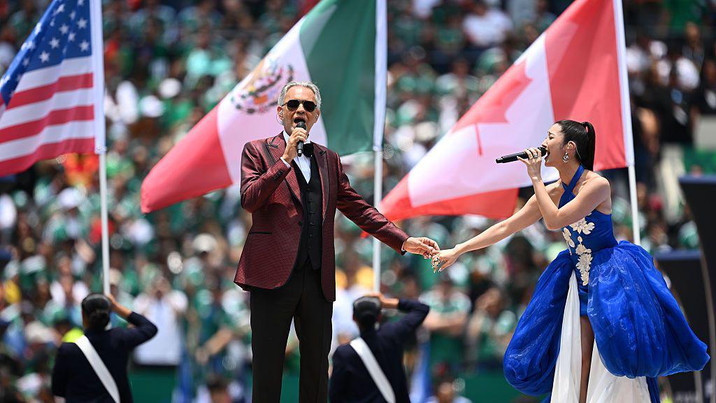 Andrea Bocelli and EJAE singing on stage.