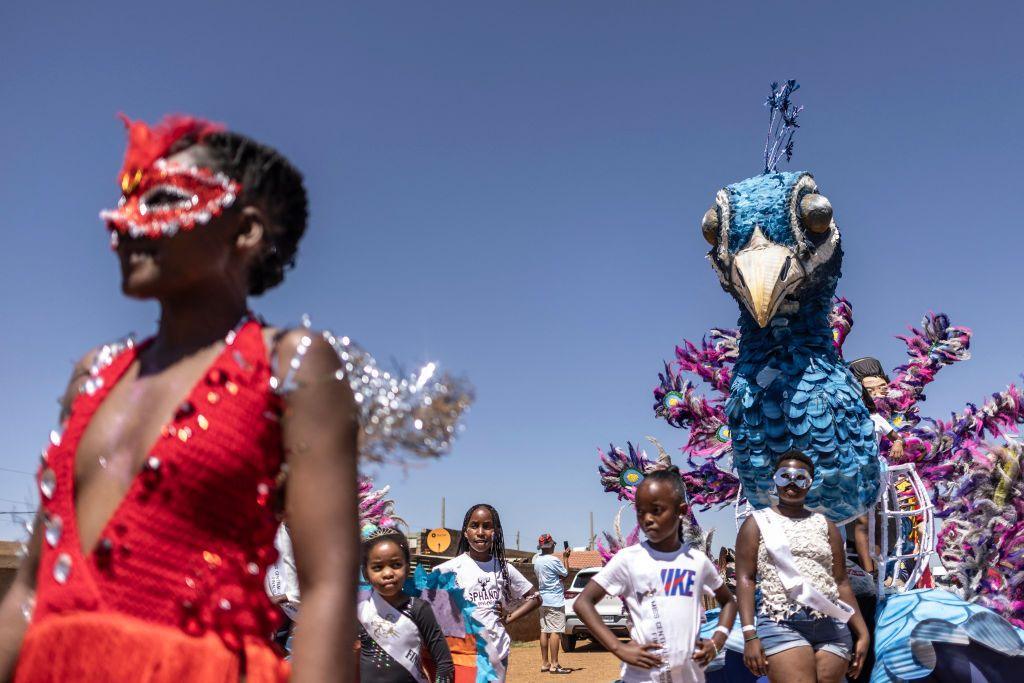 People parade in bejewelled masks and large bird effigies.