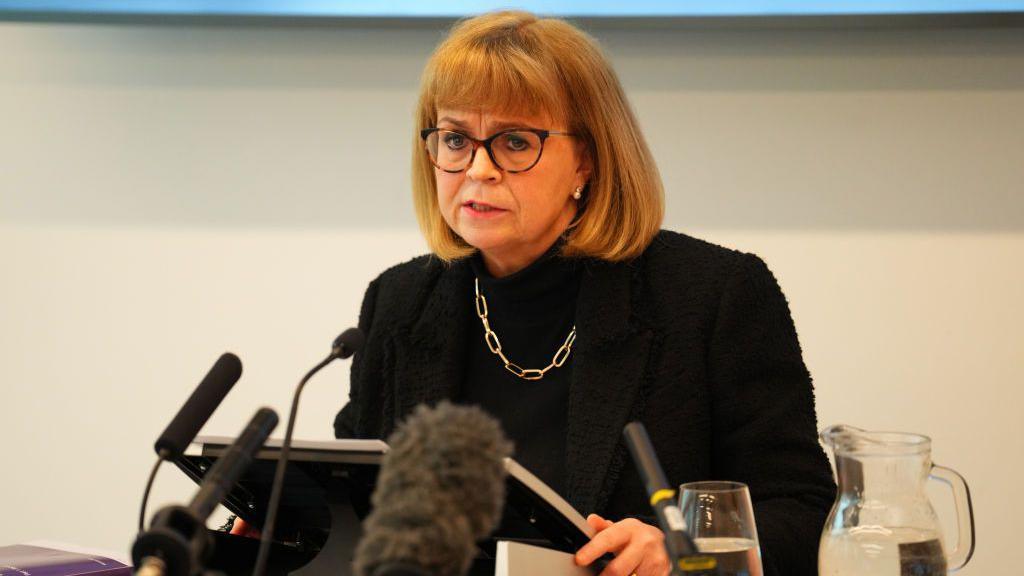 Lady Elish Angiolini sitting behind microphones