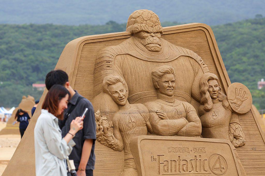 A man and a woman in front of a sand art pyramid of Fantastic Four characters